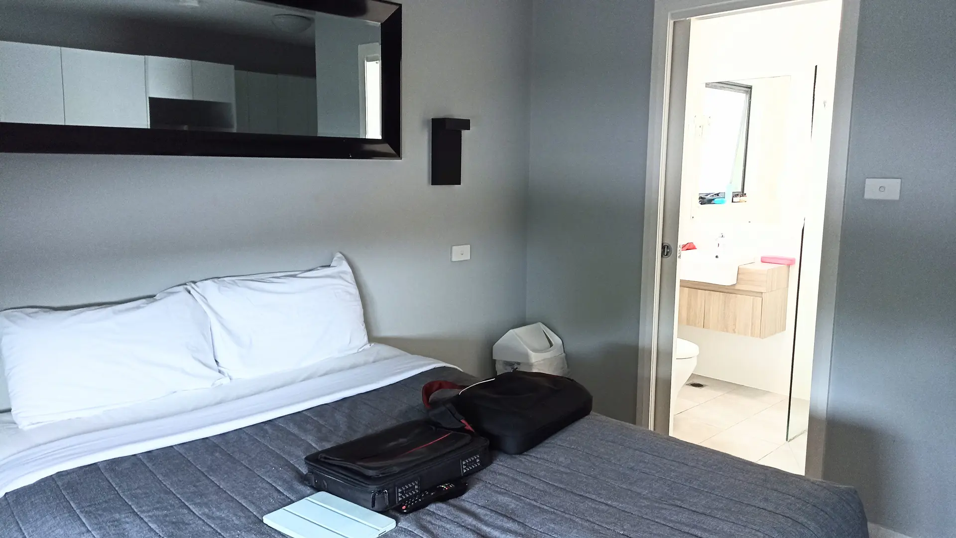 Studio bedroom with mirrored cabinet, wall sconce and ensuite bathroom view