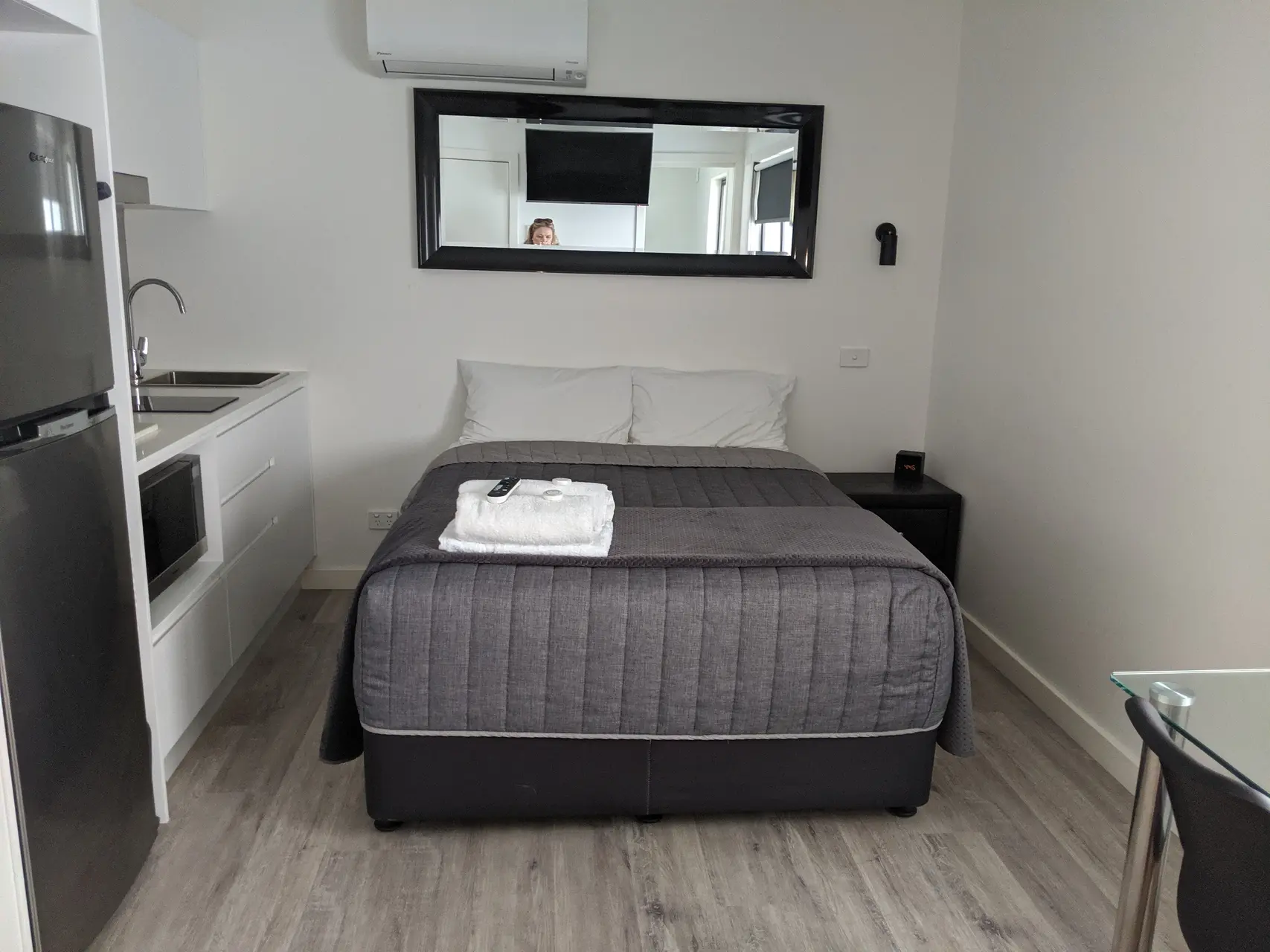 Studio apartment interior with queen bed, framed art, sofa with coral cushion and dining nook